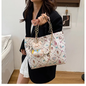 Detailed view of white tote bag with colorful cartoon prints and plush bear pendant