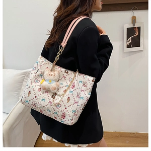 Detail of canvas tote bag with cartoon bear prints, pink strap and pearl chain decoration
