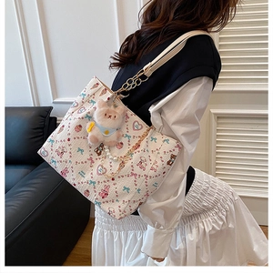 Close-up of white tote bag with cartoon animal prints and plush bear charm detail