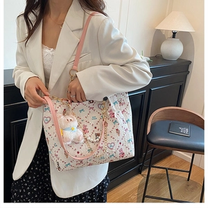 Detail of cute cartoon tote bag with pink rabbit motifs, gold chains, and pearl accents