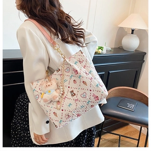 Detail of white cartoon tote bag featuring bear print, pink strap, and pearl chain