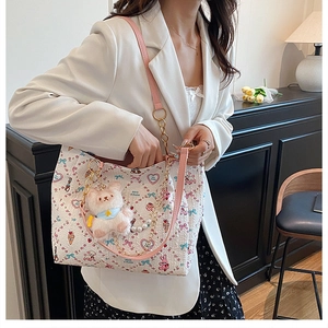 Detail of cute cartoon tote bag with pink bow prints and plush rabbit charm