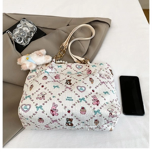 Detail of white quilted tote with cute cartoon prints, pearl chain, and plush charm