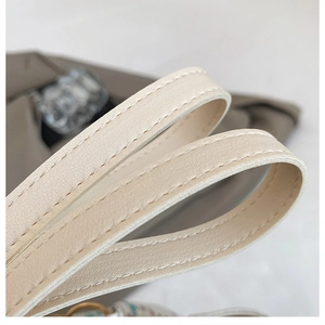 Close-up of beige leather tote bag handles featuring reinforced double stitching detail