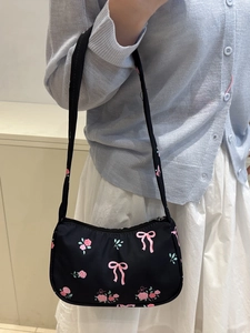 Borsa a tracolla nera con stampa a rose e fiocchi indossata da una modella