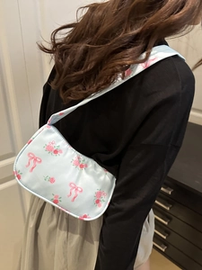 Borsa a spalla in raso blu con stampe di rose rosa e fiocchi indossata da modella