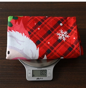 Detailed view of lightweight 80.3g red plaid Santa chair cover on an electronic scale