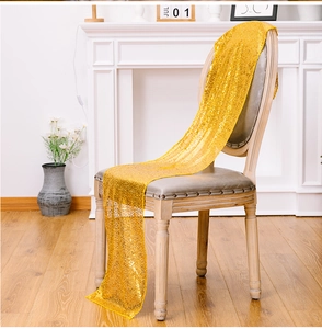 Dettaglio del runner da tavola con paillettes dorate e un elegante drappeggio su sedia