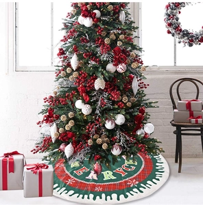 Close-up of green Christmas tree skirt with red plaid snowflake and Merry Christmas text
