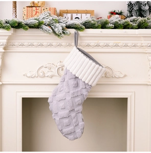 Calcetín de Navidad de felpa gris con textura de punto en una chimenea blanca