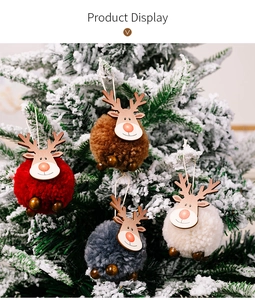 Détail de quatre suspensions rennes en peluche avec visages en bois sur un sapin enneigé
