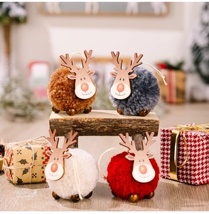Détail de suspensions rennes de Noël en pompons de peluche et bois sur fond de fête chaleureux