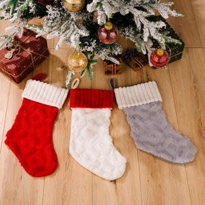 Juego de tres calcetines navideños de felpa en rojo blanco y gris sobre suelo de madera