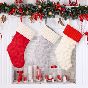 Tres calcetines de Navidad de felpa en rojo, gris y blanco colgados en una chimenea