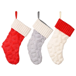 Tres calcetines de Navidad de felpa en rojo, gris y blanco con lazos para colgar