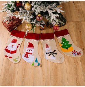 Detailed view of four rustic Christmas stockings with festive embroidery on wood floor
