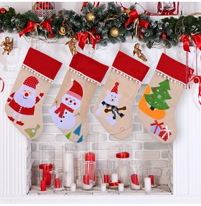 Close-up of four linen Christmas stockings with cartoon motifs hanging on a cozy fireplace