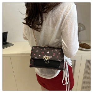Detail of floral and bow print shoulder bag with gold chain strap and metal lock