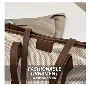 Close-up of canvas texture and brown leather stitching on a large commuter tote bag
