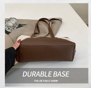 Detail shot of the durable brown leather base and reinforced stitching of the tote bag