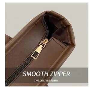 Detailed macro view of smooth gold-tone zipper on a textured dark brown leather tote bag