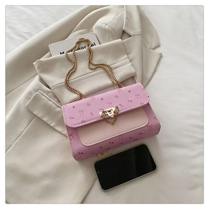 Détail du sac cerise rose avec cuir grainé et bandoulière en chaîne dorée élégante