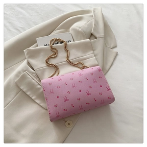 Détail de la pochette rose avec imprimé nœuds et bandoulière en chaîne dorée