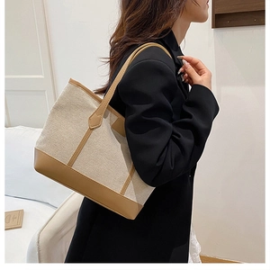 Detail of canvas tote bag with brown leather trim carried on shoulder for daily commute