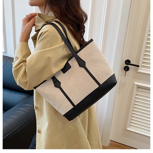 Close-up of beige canvas and black leather detail on the large shoulder tote bag