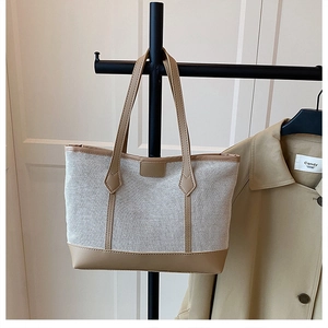 Detail of canvas and khaki leather tote bag featuring contrast stitching and sturdy handles