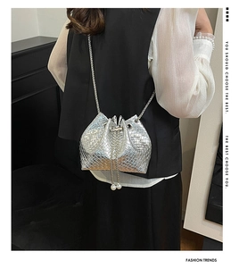 Close-up of silver woven bucket bag with pearl drawstring and metal chain strap