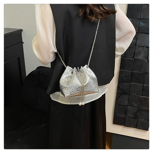 Close-up of silver woven bucket bag with pearl tassels and metal chain strap