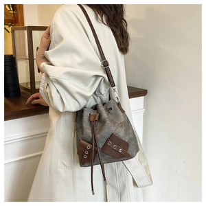 Detail of grey vintage canvas bucket bag with brown leather patches and drawstring closure