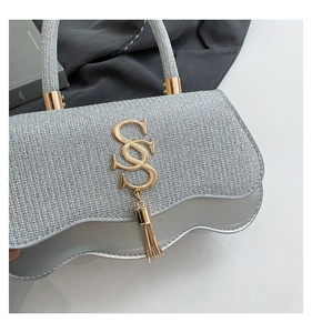 Detail of silver sequined handbag with golden S-logo, fringe tassel and metallic handle
