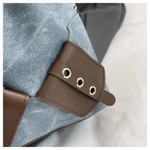 Detailed macro view of blue denim fabric stitched with brown leather and silver eyelets