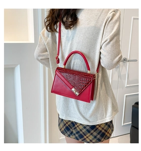 Detail of red crocodile texture handbag with silver square lock on a model