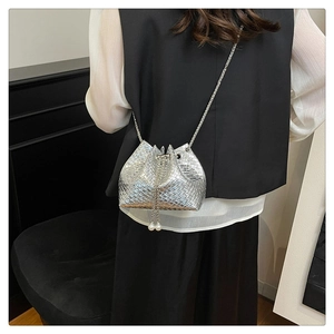 Detail of silver woven bucket bag with pearl drawstring and elegant chain strap