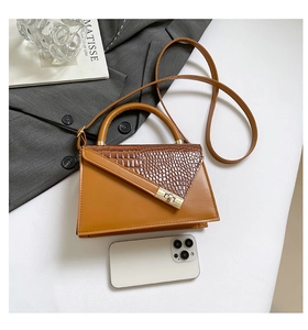 Detail of elegant brown handbag with croc-embossed texture and golden metal lock