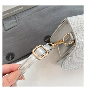 Close-up of silver sequin evening bag with gold swivel clasp and grey leather strap