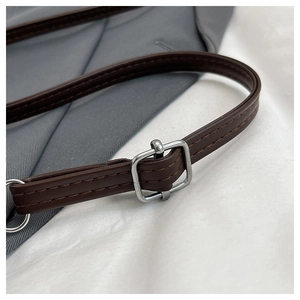 Detail of adjustable PU leather strap with silver buckle and stitching on bucket bag