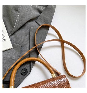 Detail of a brown crocodile pattern leather handbag with elegant gold metal hardware