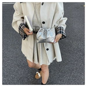Detail of silver woven bucket bag with pearl drawstring and metal chain strap