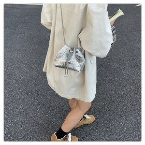 Detail of silver woven bucket bag with metallic texture and pearl drawstring accents
