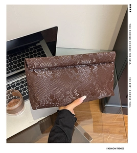 Detail of dark brown python-textured clutch bag in a professional office setting