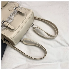 Vue détaillée du sac à dos en cuir beige avec bordure en dentelle et boucles métalliques