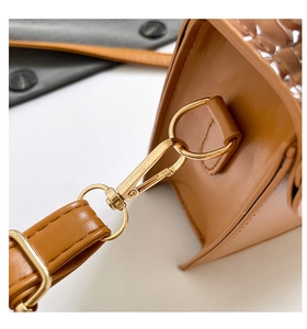Detail of gold metal hardware and crocodile texture on brown leather handbag