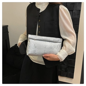 Close-up of silver snakeskin textured clutch bag with shiny metallic finish details