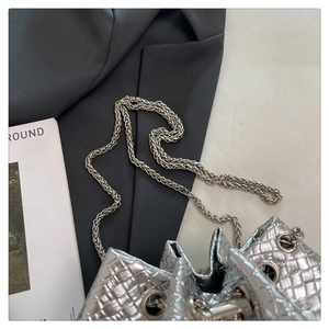 Close-up of silver bucket bag featuring grid texture, chain strap, and metallic finish