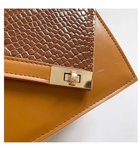 Detail of elegant two-tone handbag with crocodile pattern leather and gold twist lock