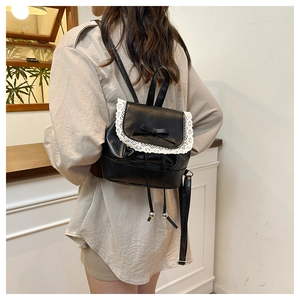 Close-up of black matte leather backpack with white lace trim and bow knot detail